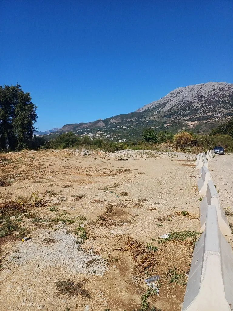 Pogled na zemljište sa putem i planinama u pozadini.