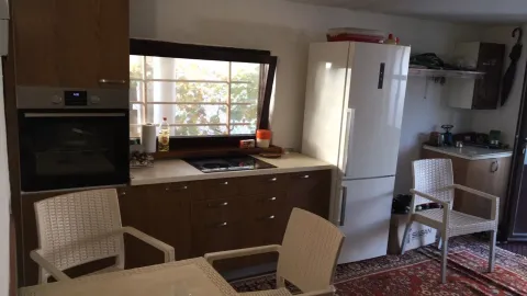 Kitchen with wooden cabinets, appliances, and a dining table. - image 21