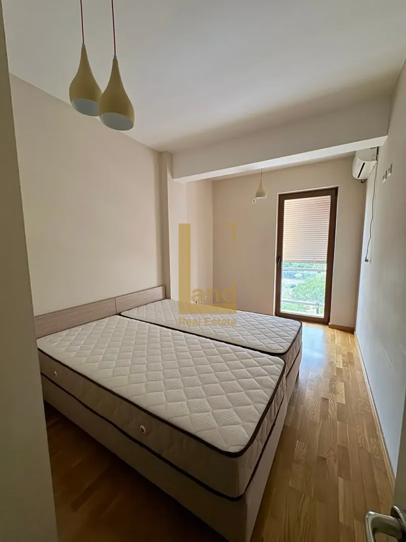 Svjetla spavaća soba sa bračnim krevetom i drvenim podom.