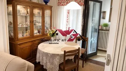 Trpezarija sa drvenim stolom, stolicama i velikom vitrinom u stanu. - image 3