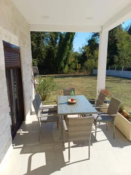 Covered terrace with a dining table and chairs overlooking the yard. - image 8