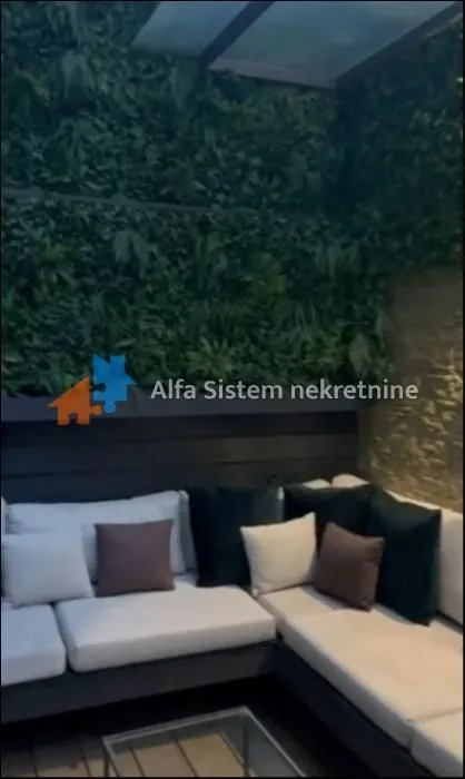 Natkrivena terasa sa garniturom za sedenje i vertikalnim zelenim zidom.
