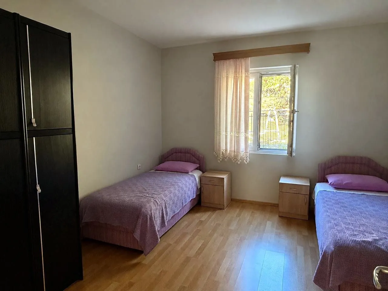 Bedroom with two single beds, a wardrobe, and a window.