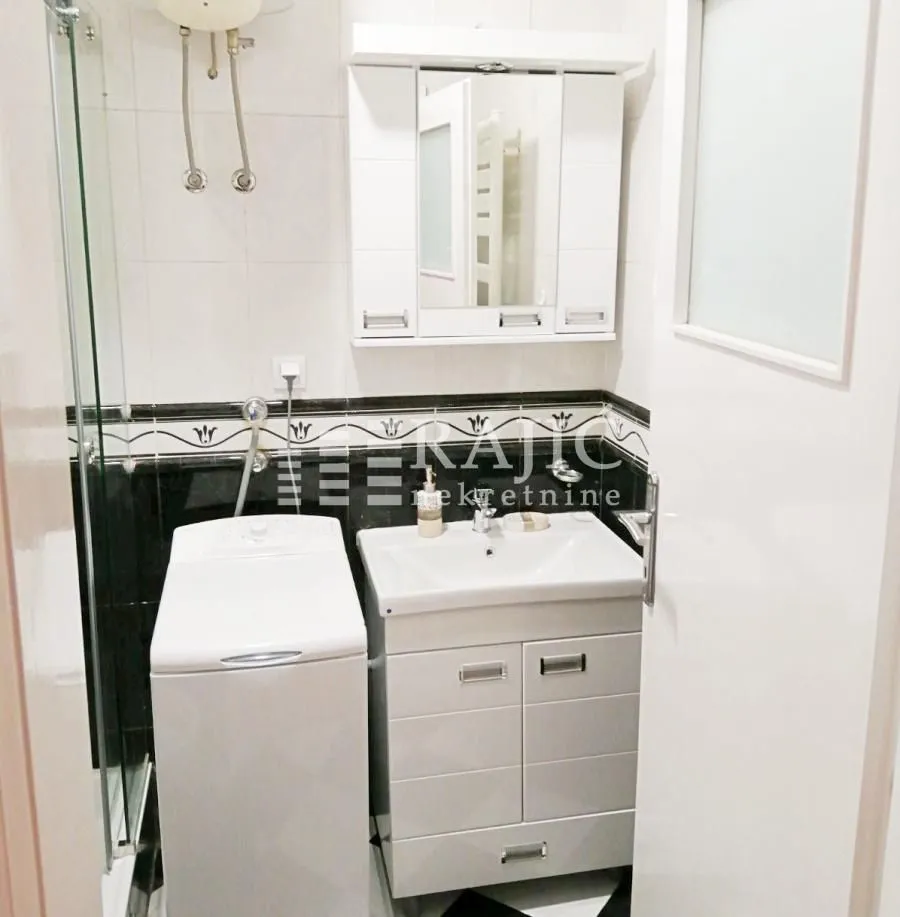 Small bathroom with a sink, mirror, washing machine, and shower cabin.