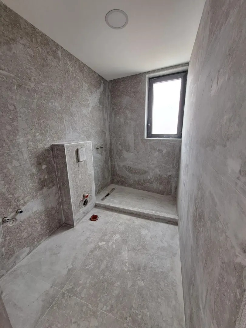 Nedovršeno kupatilo sa sivim pločicama.