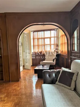 Living room with wooden wall paneling and a view of the seating area. - image 7