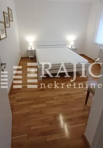 Bright bedroom with a double bed and wooden flooring.