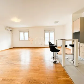 Spacious living room with wooden flooring and a bar counter with kitchen area. - image 12