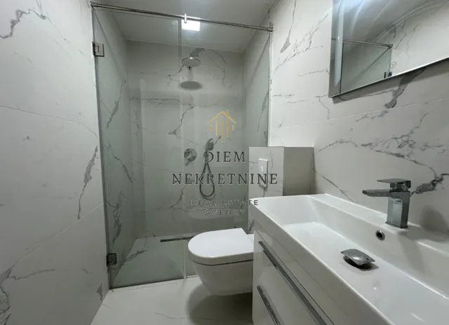 Modernly equipped bathroom with a walk-in shower and marble tiles.