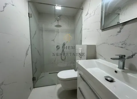 Modernly equipped bathroom with a walk-in shower and marble tiles. - image 12