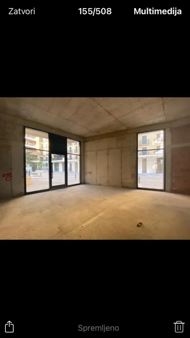 Unfurnished space in grey phase with large windows and a courtyard view.