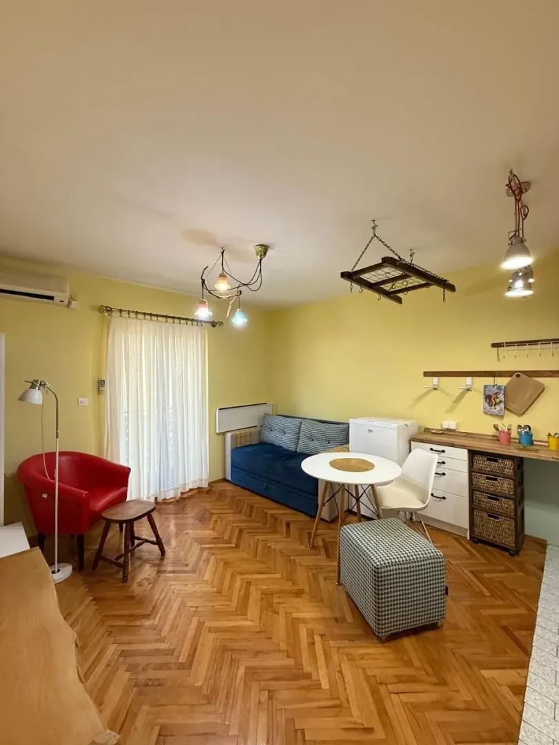 Living room with a seating area, dining table, and parquet flooring.