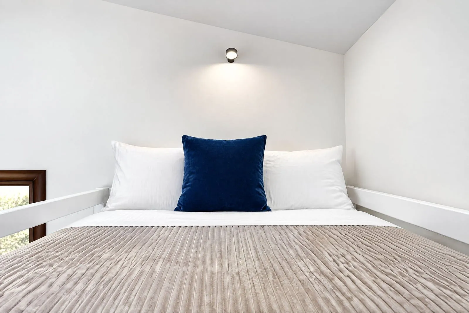 Tidy bedroom with a bed and a wall lamp.
