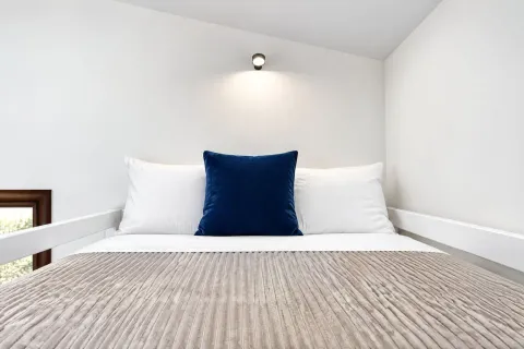 Tidy bedroom with a bed and a wall lamp. - image 14
