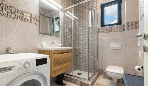 Moderno opremljeno kupatilo sa tuš kabinom, umivaonikom i veš mašinom. - image 4