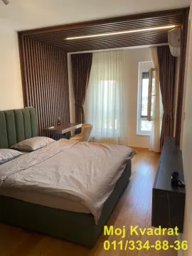Moderna spavaća soba sa bračnim krevetom, drvenim zidnim panelima i radnim stolom. - image 5