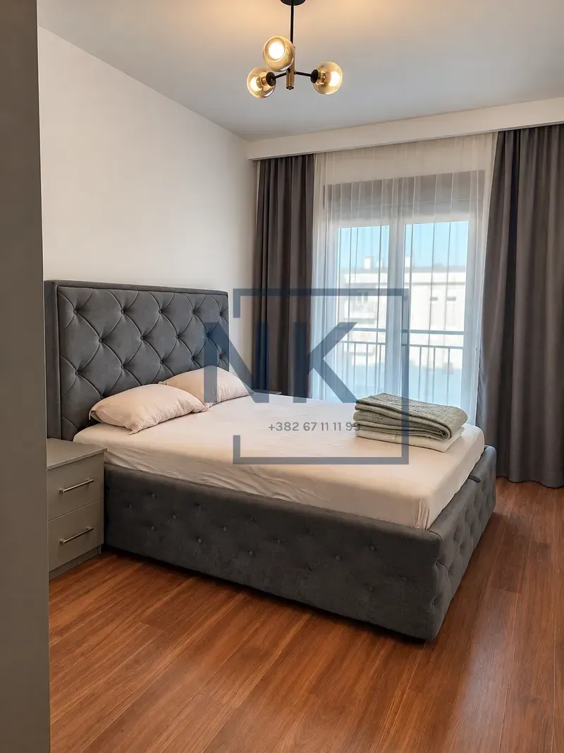 Furnished bedroom with a double bed, nightstand, and a window with natural light.