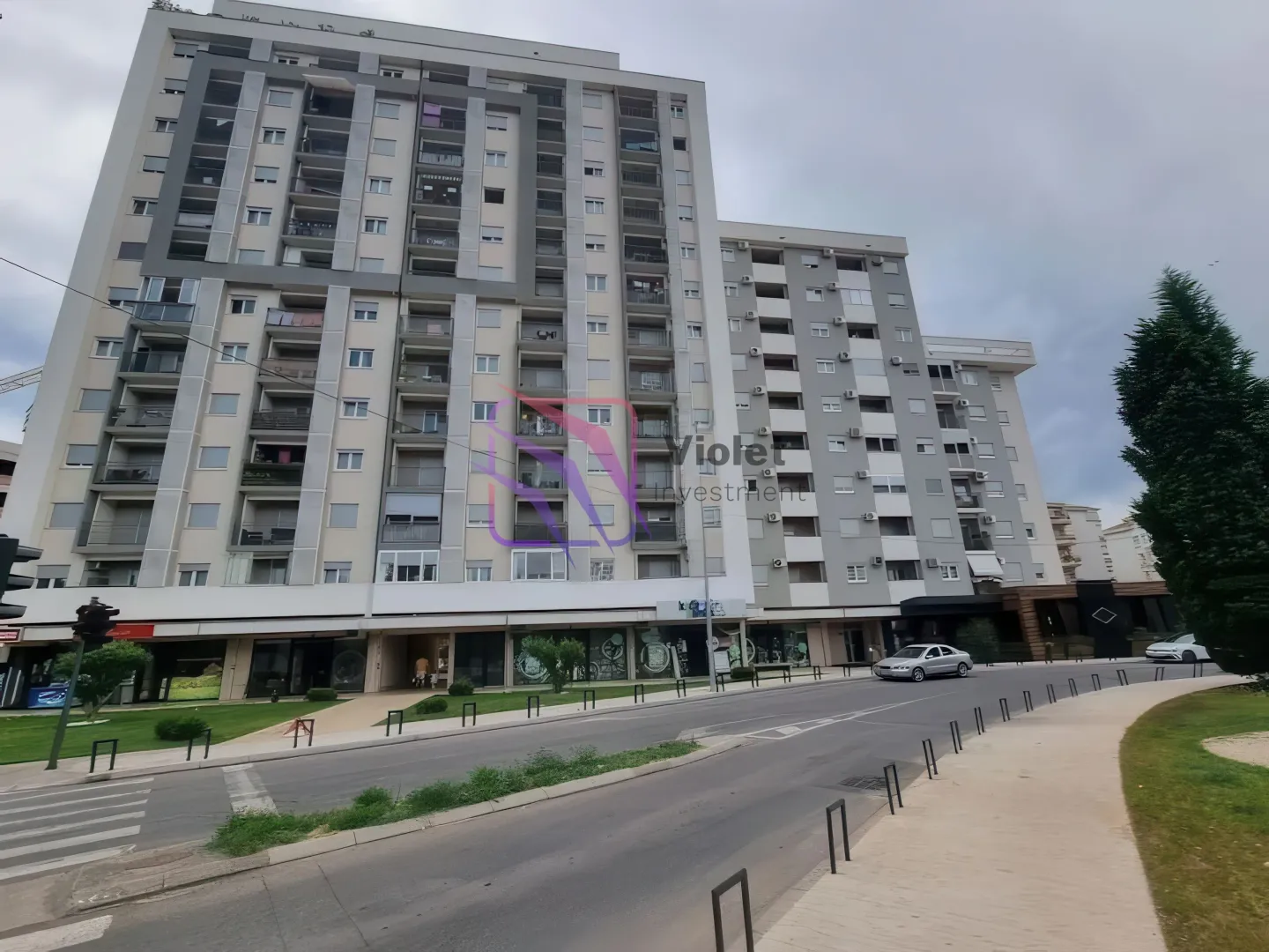 Pogled na spoljašnjost moderne stambene zgrade sa poslovnim prostorom u prizemlju.