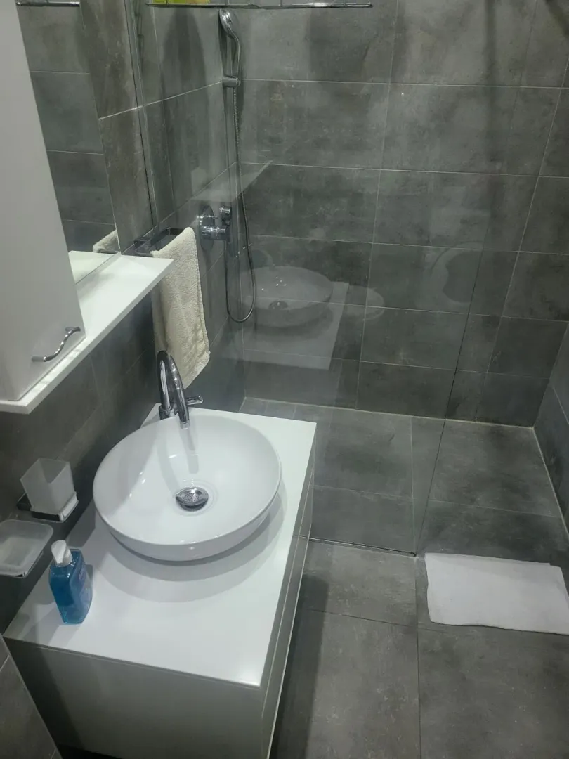 Modern bathroom with grey tiles and a walk-in shower.