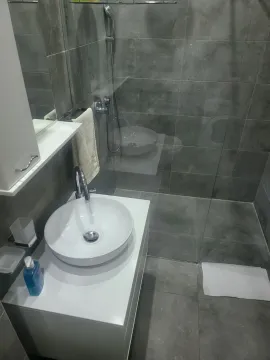 Modern bathroom with grey tiles and a walk-in shower. - image 19