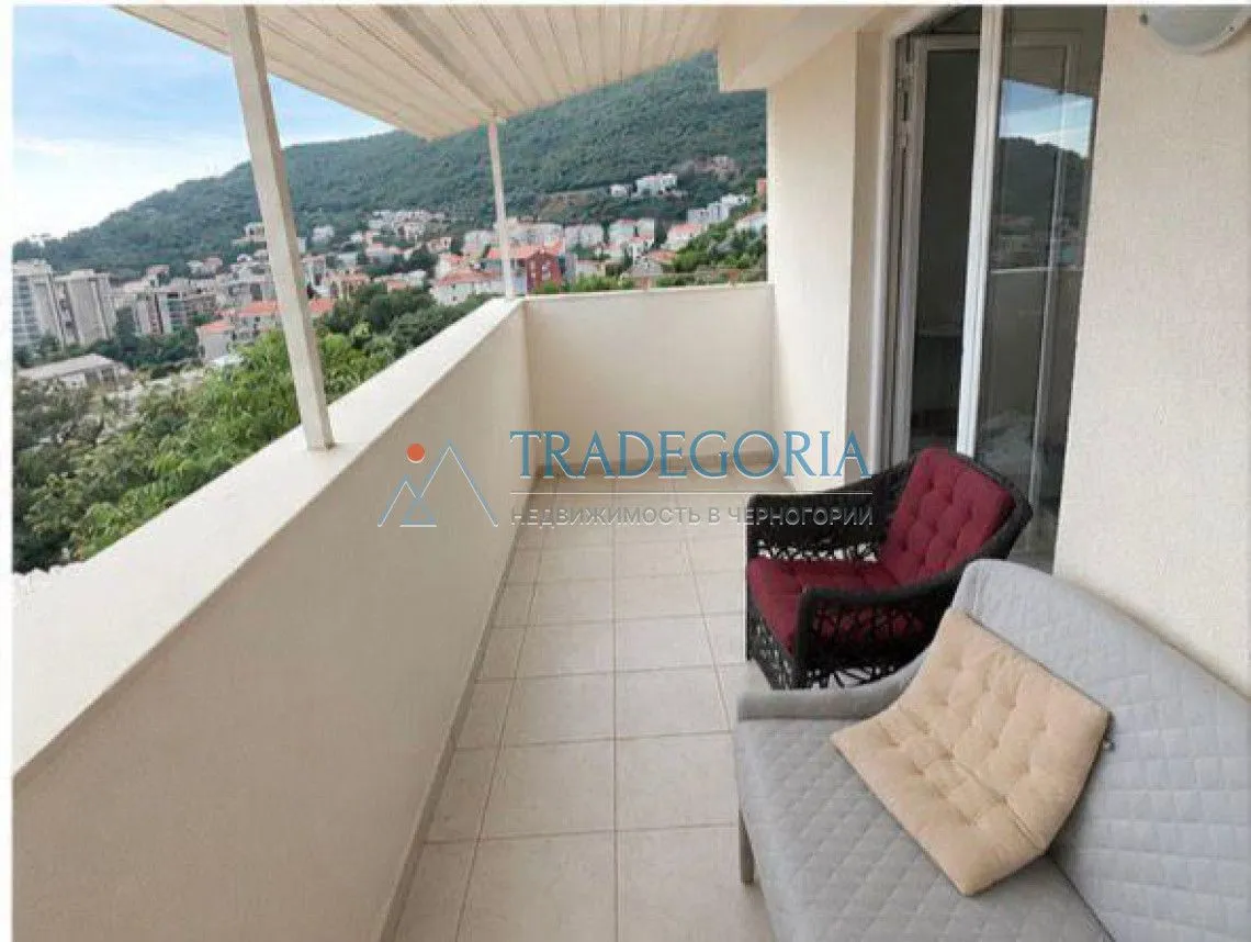 Natkriveni balkon sa garniturom za sjedenje i pogledom na naselje.