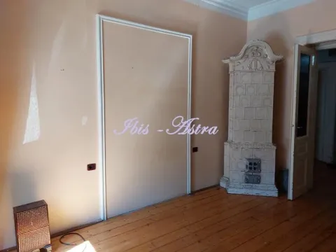 Empty room with wooden flooring, a tiled wood stove, and a doorway. - image 5