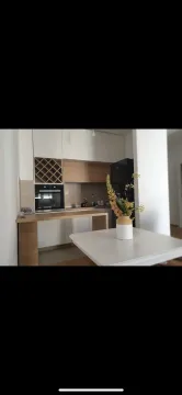 Modern kitchen with light cabinets, a built-in oven, and a dining table. - image 11