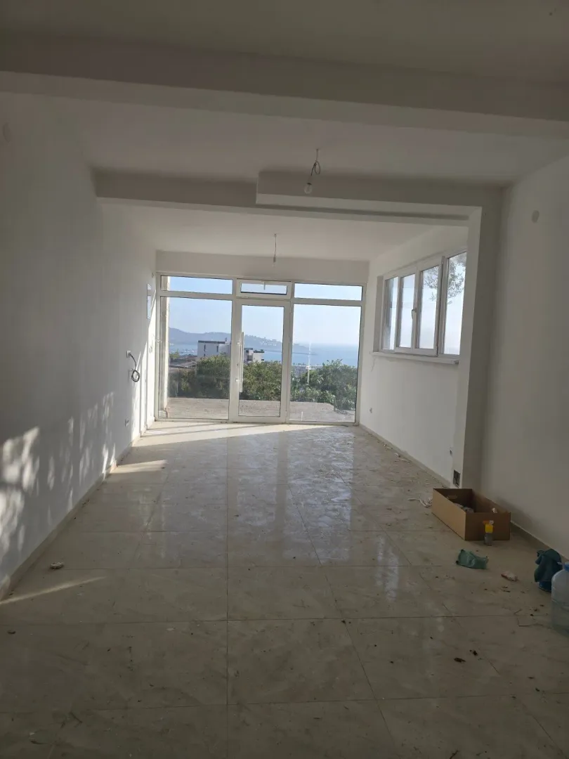 Prazna, nezavršena prostorija sa velikim staklenim portalom i pogledom na more.