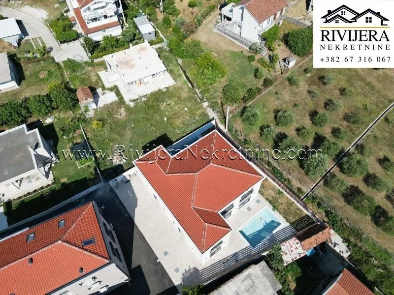 Aerial view of a house with a red tile roof and a swimming pool.