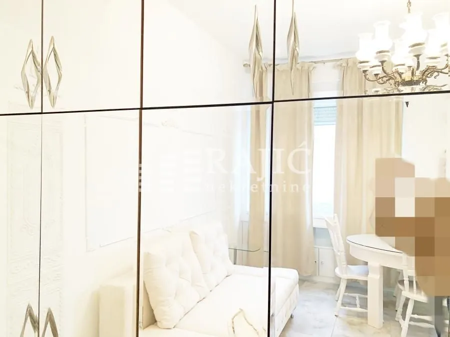 Living room with a white sofa set and dining table, reflected in the mirror.