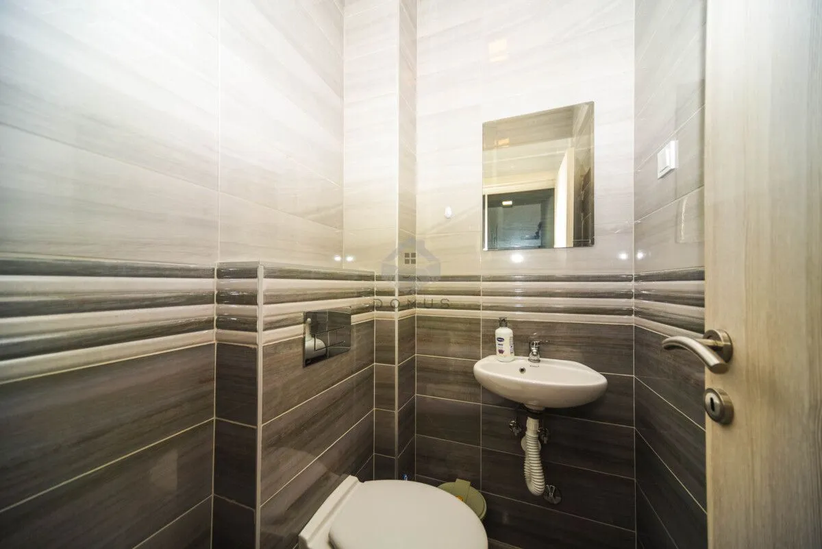 Manje kupatilo obloženo keramičkim pločicama sa umivaonikom i wc šoljom.