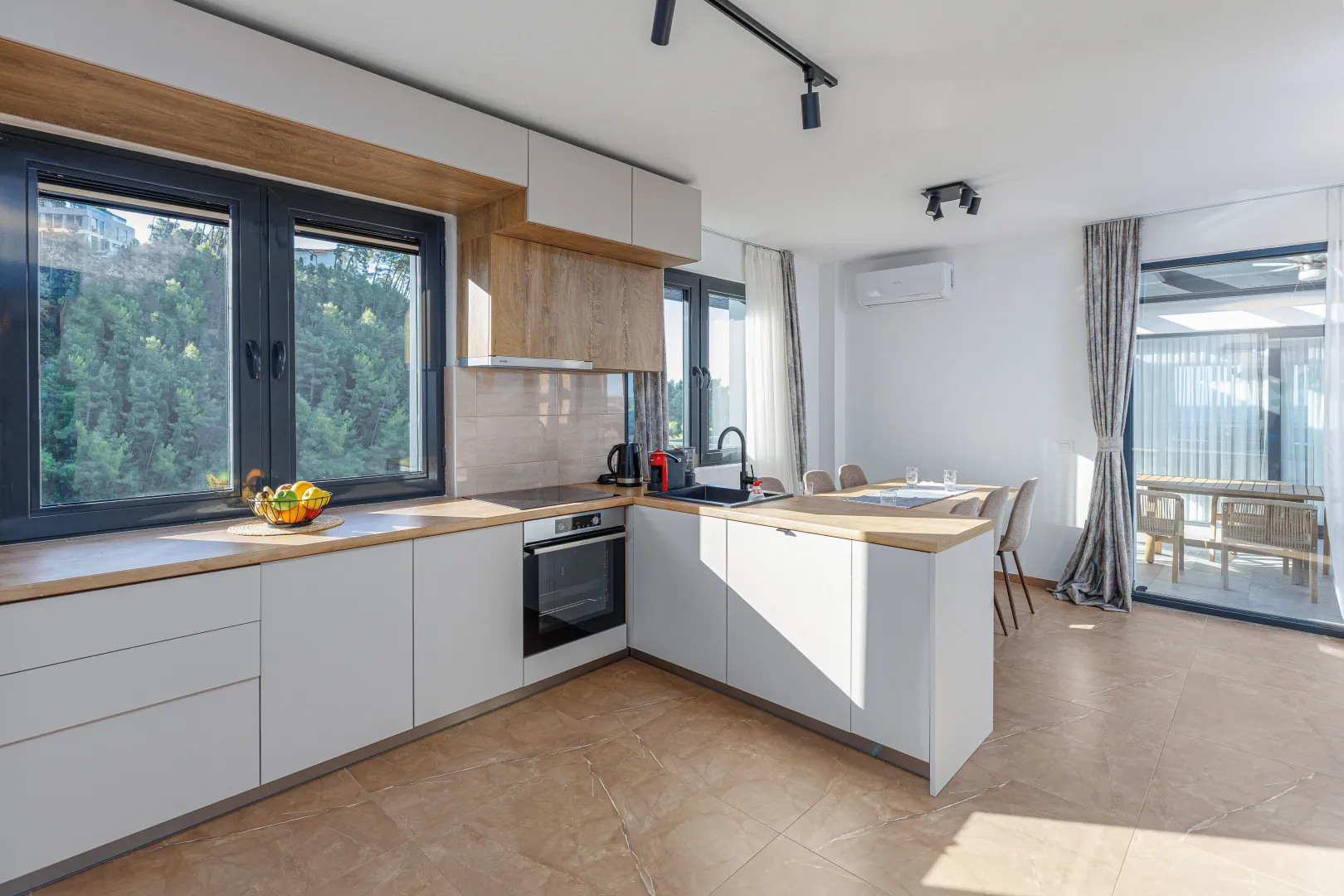 Modern kitchen with built-in appliances, dining area and access to the terrace.