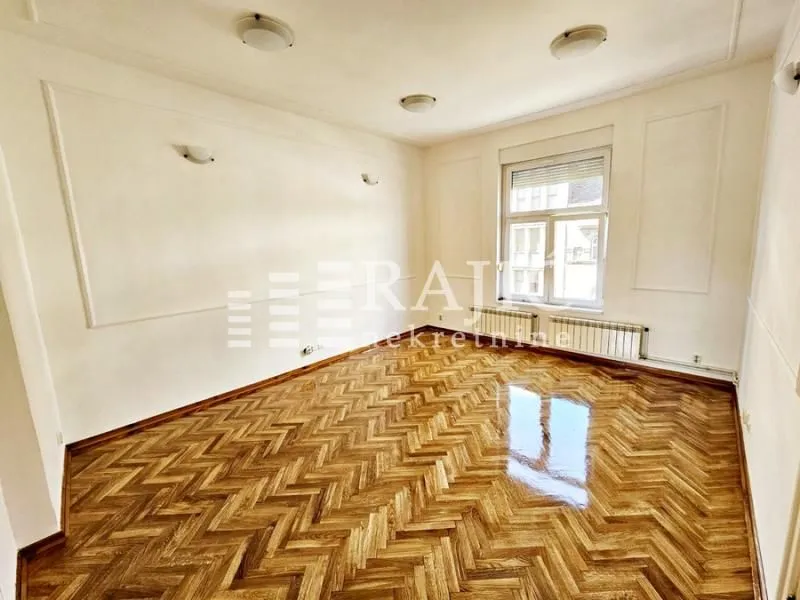 Empty room with parquet flooring and white walls.