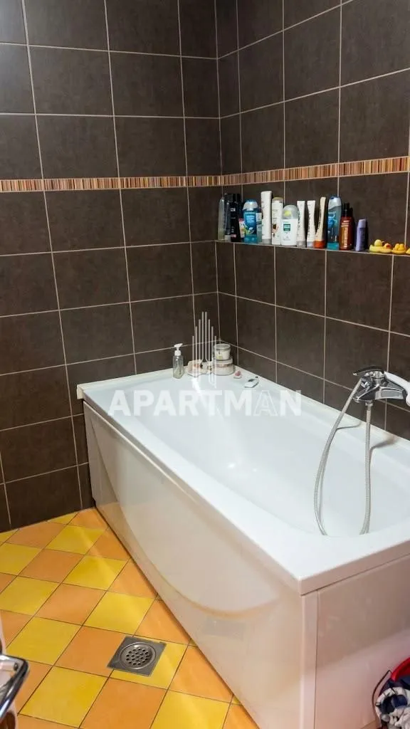 Bathroom with a bathtub and dark wall tiles.