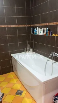 Bathroom with a bathtub and dark wall tiles. - image 2