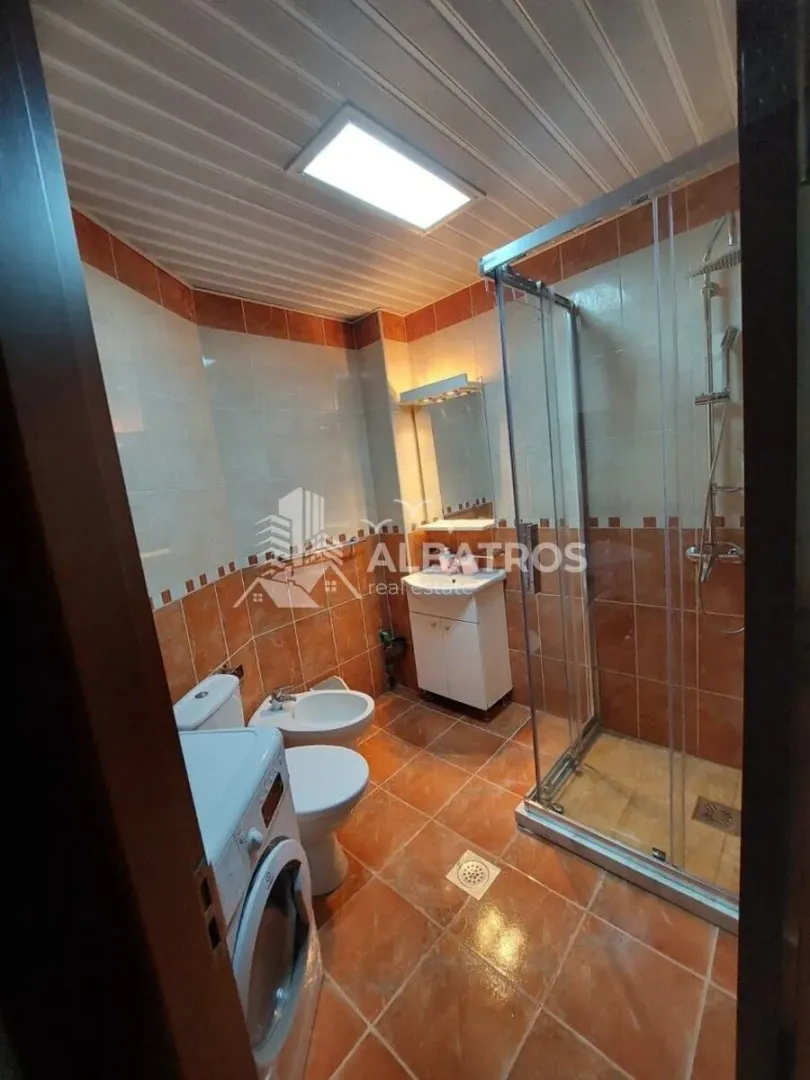 Bathroom equipped with a shower cabin, sink, toilet, and washing machine.