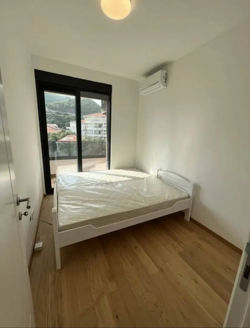 Svjetla spavaća soba sa krevetom i izlazom na terasu.
