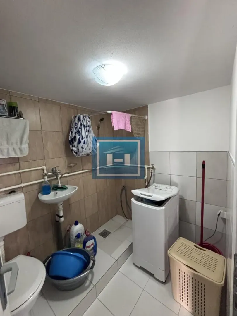 Manje kupatilo sa tuš kabinom, umivaonikom i veš mašinom.