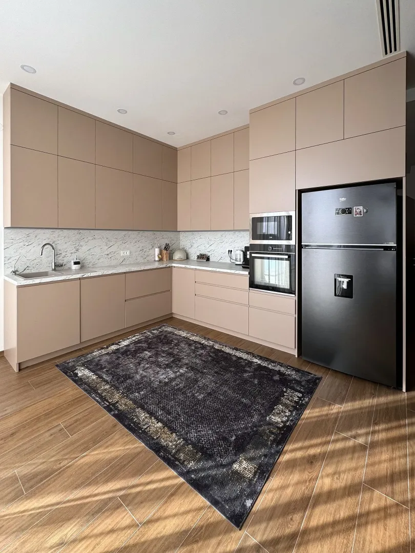 Modern kitchen with beige cabinets, built-in appliances, and a black refrigerator.