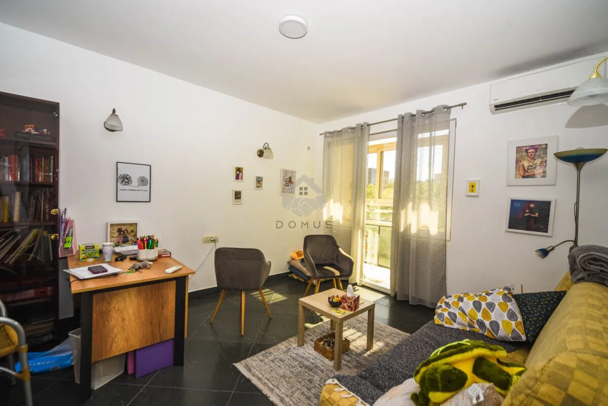 Living room with a desk, sofa, and balcony access.