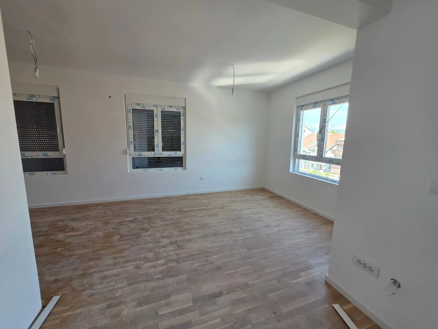 Empty bright room with parquet flooring and white walls.