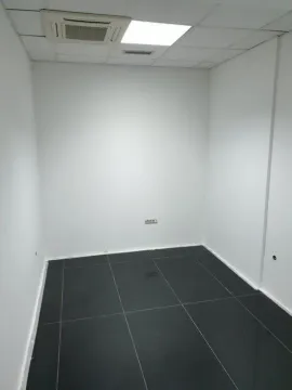 Empty office room with white walls and dark floor tiles. - image 9