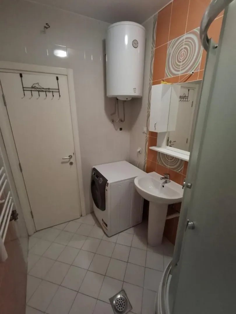 Bathroom with a washbasin, washing machine, water heater and shower cabin.