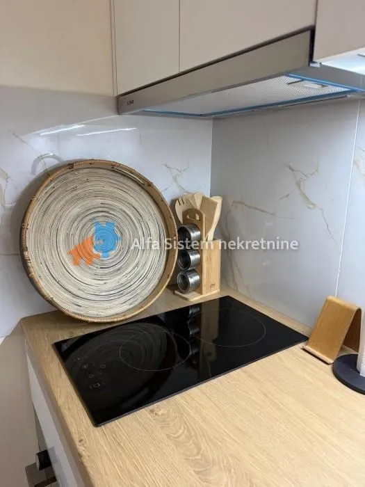 Pogled na deo kuhinje sa ugradnom pločom i kuhinjskim elementima.