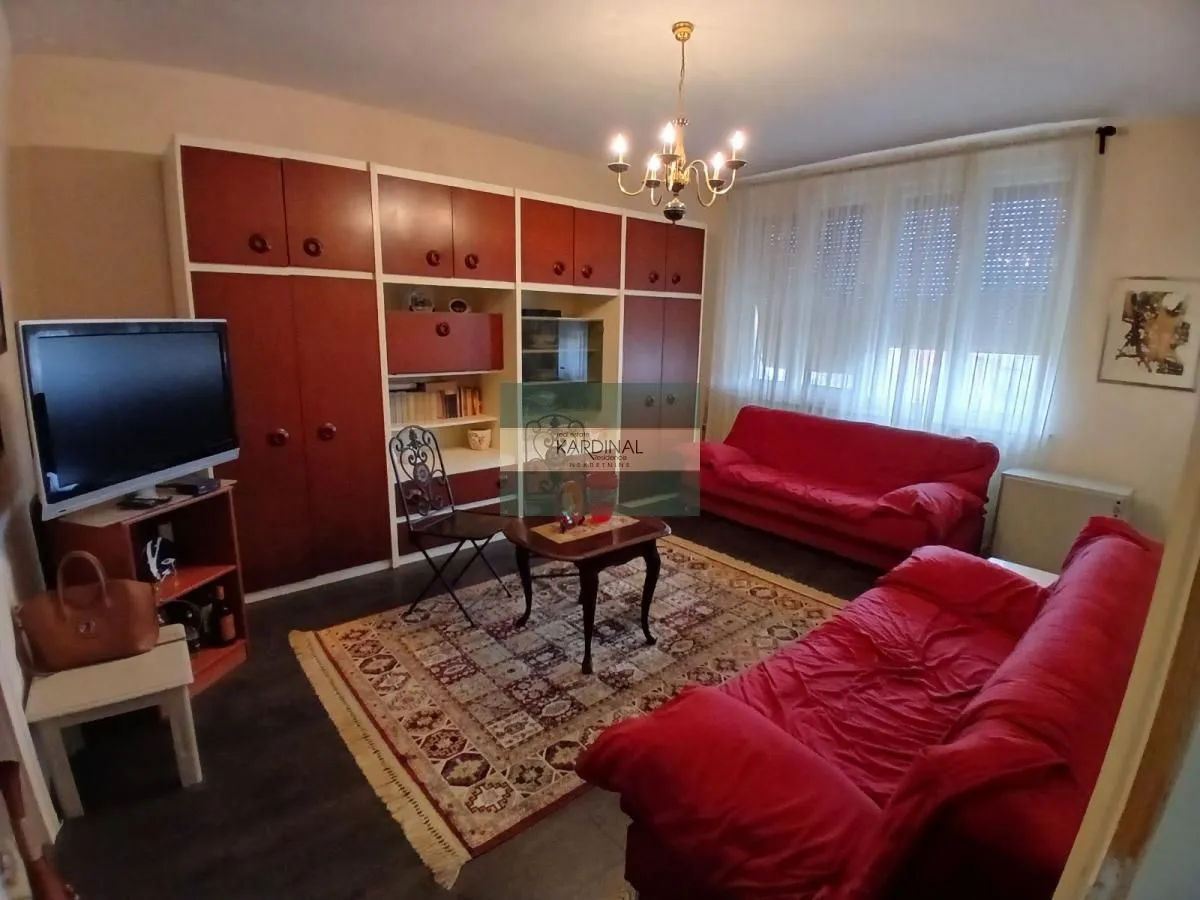 Dnevna soba sa garniturom za sedenje, televizorom i ugradnim ormarima.
