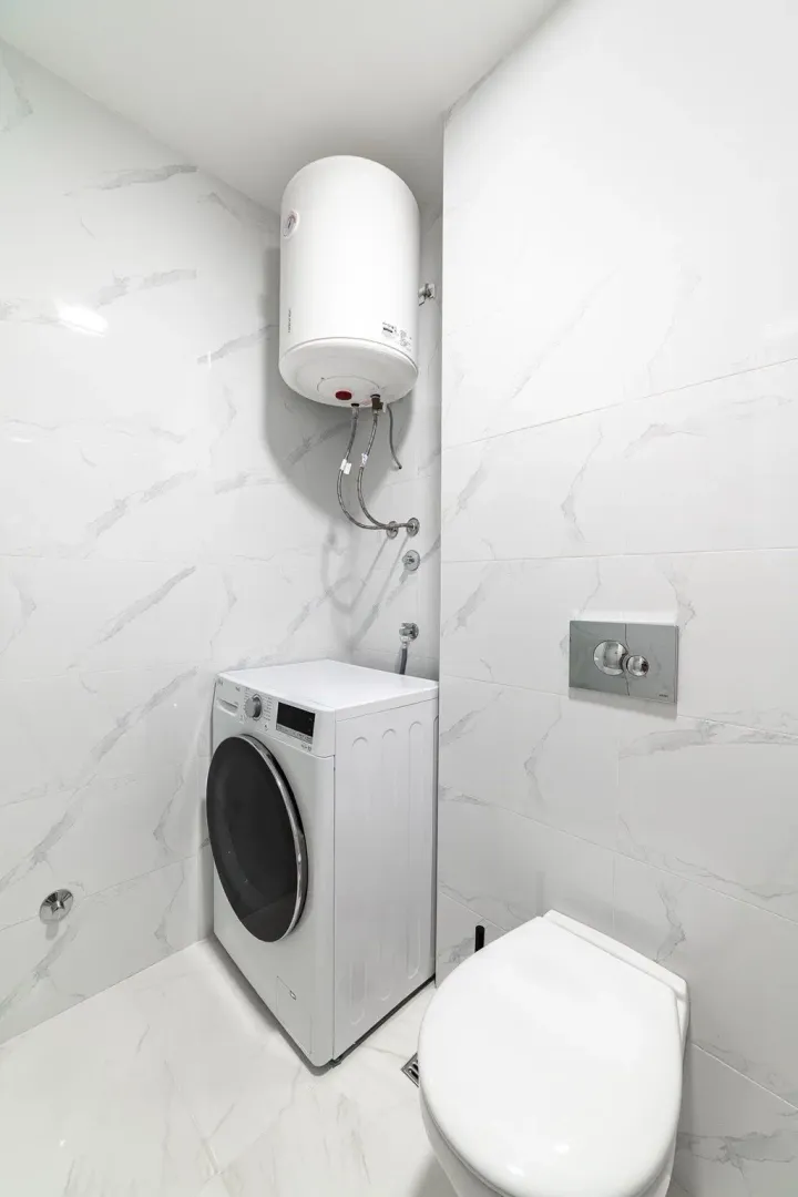 Moderno opremljeno kupatilo sa veš mašinom i ugradnim bojlerom.