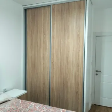 A bedroom featuring a built-in wardrobe with sliding wooden doors. - image 10
