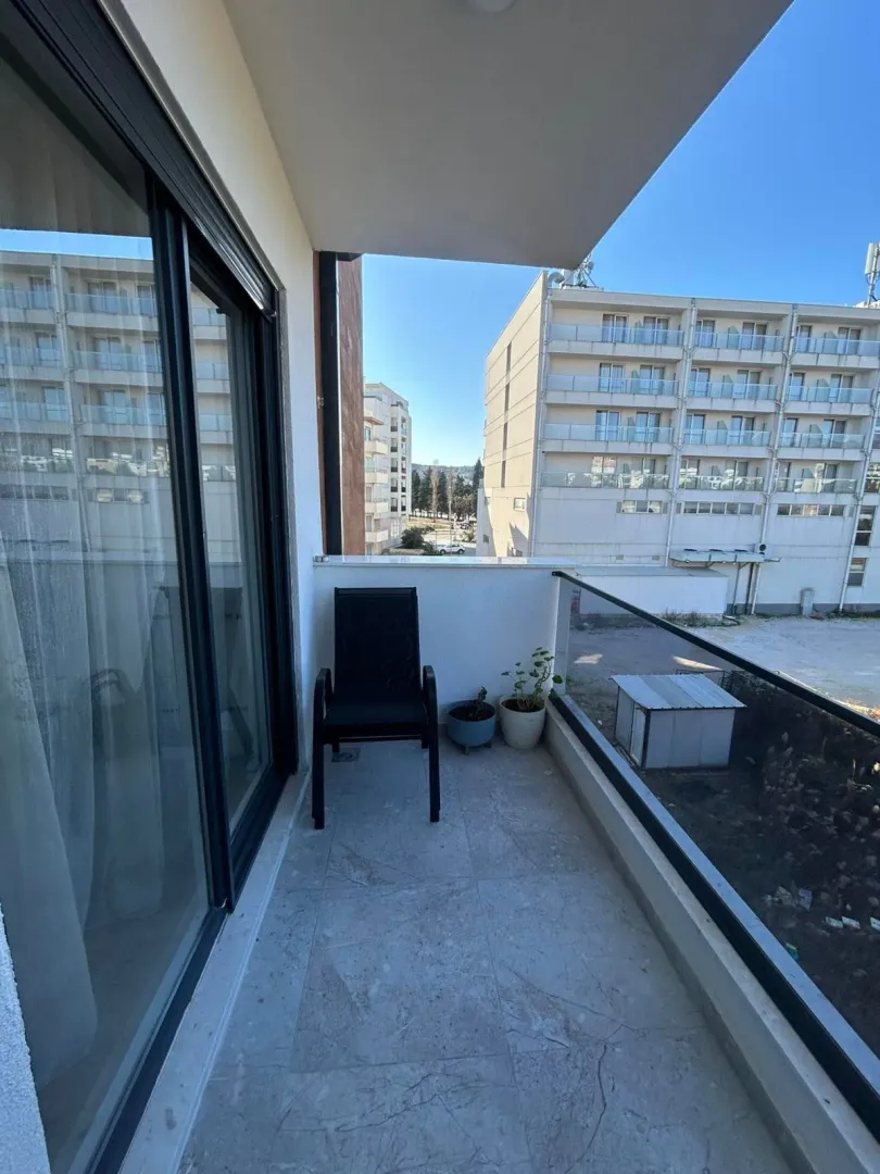Small covered balcony with a glass railing and a chair.
