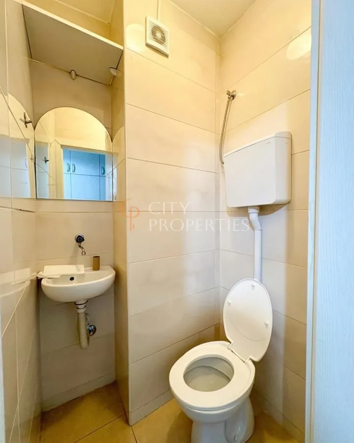 Manje kupatilo obloženo keramičkim pločicama sa umivaonikom i wc šoljom.