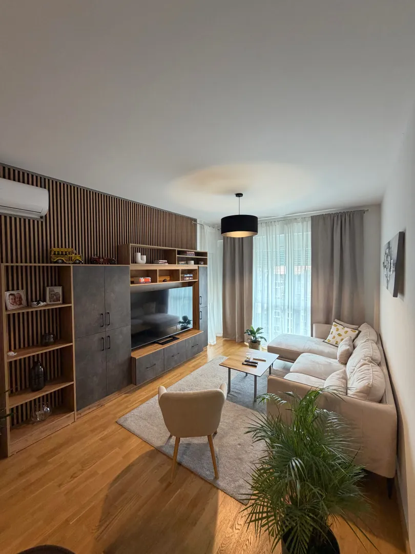 Modern living room with a sofa, large TV, and wooden wall panels.